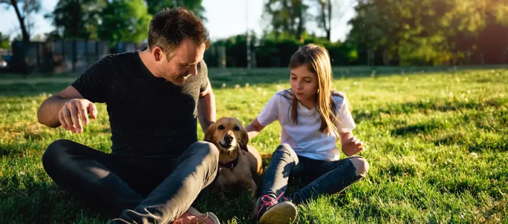 Man, girl, and dog enjoying sunny park.